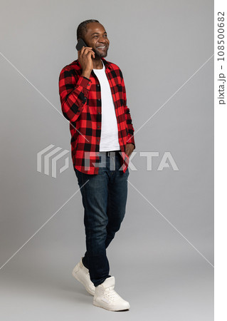 Happy black bearded man wearing red checkered shirt talking on smartphone 108500682