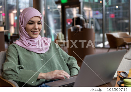 Young woman in hijab working in a cafe and looking contented 108500713