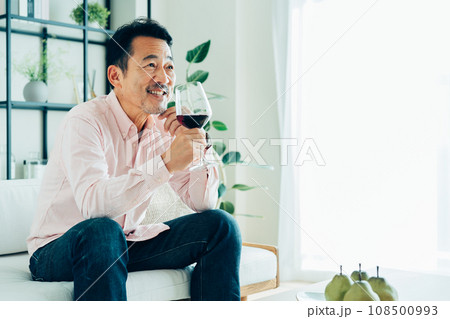 リビングで赤ワインを飲むミドルの男性 リビングで赤ワインを飲むミドルの男性 108500993