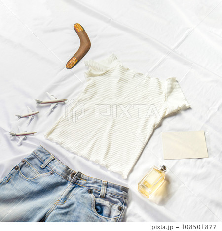 On the table were models card, perfumes and notebooks lying around a white shirt and jeans. 108501877