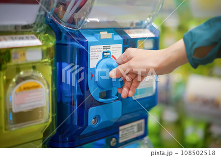 A human hand in a turquoise sweater is twisting a blue gashapon machine to release a figure. In Japan, it is considered as one of the most well liked risks. 108502518