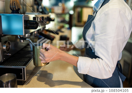 Coffee shop assistant preparing coffee in a coffee store Coffee shop assistant preparing coffee in a coffee store 108504105