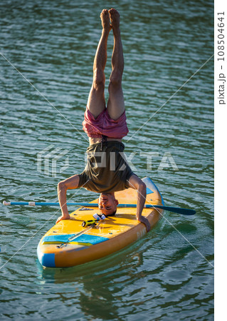 Man practicing yoga on SUP board. Man practicing yoga on SUP board. 108504641
