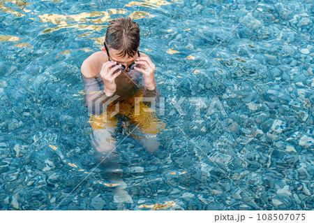 Boy swims with goggles swims in clear ocean water Boy swims with goggles swims in clear ocean water 108507075
