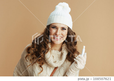 happy stylish female in beige sweater, mittens and hat 108507621