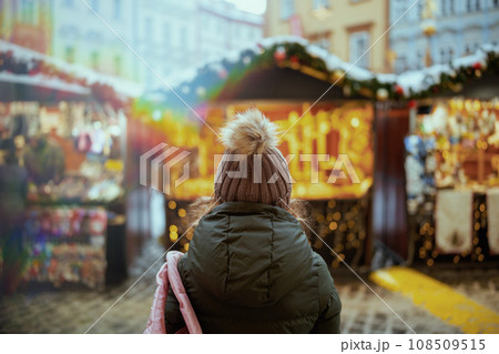 woman in green coat and brown hat at christmas fair in city woman in green coat and brown hat at christmas fair in city 108509515