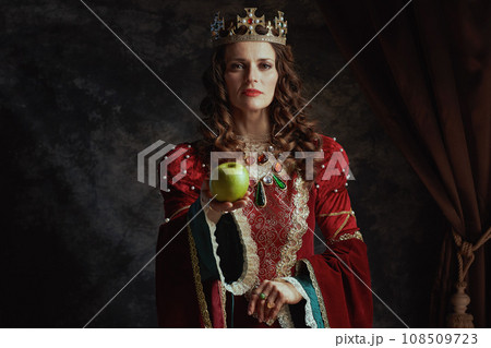 medieval queen in red dress with green apple and crown medieval queen in red dress with green apple and crown 108509723