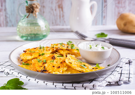 Potato latkes with herbs and sour cream on a plate on the table Potato latkes with herbs and sour cream on a plate on the table 108511006