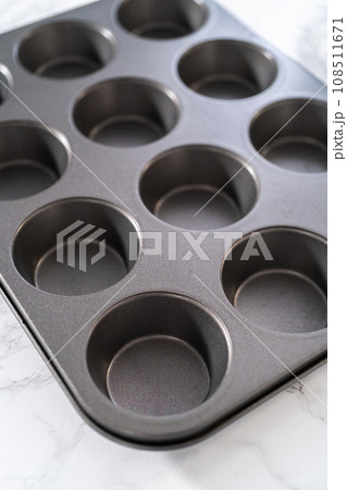 Close-up view. Metal baking pans for cupcakes on a marble countertop. 108511671