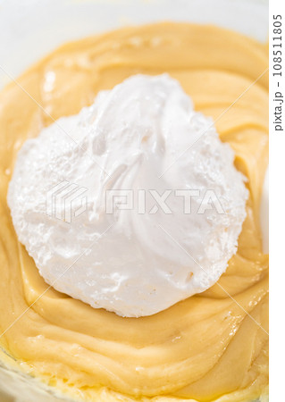Melting chocolate chips and other ingredients in a glass mixing bowl over boiling water to prepare candy corn fudge. 108511805