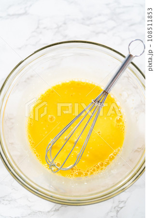 Lemon wedge cookies with lemon glaze. Mixing wet ingredients in a large glass mixing bowl to bake lemon wedge cookies. 108511853