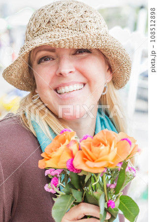 Smliing Blonde Woman Wearing a Hat Holding a Fresh Cut Floral Bouquet at the Farmers Market. Smliing Blonde Woman Wearing a Hat Holding a Fresh Cut Floral Bouquet at the Farmers Market. 108512898