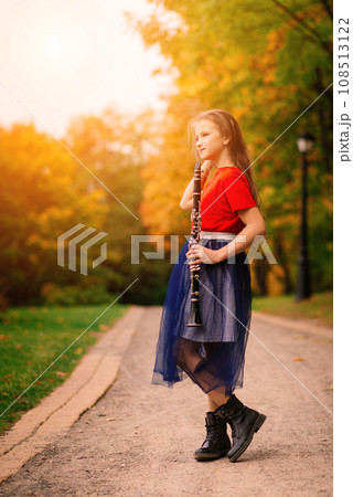 Young attractive girl playing clarinet, ebony in fall park Young attractive girl playing clarinet, ebony in fall park 108513122