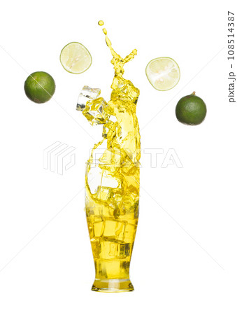 Splash spill lime juice down in ice cube glass, lime juice fall down in yellow liquid water. Green lime in juice throw splash in air. White background Isolated high speed shutter, freeze action Splash spill lime juice down in ice cube glass, lime juice fall down in yellow liquid water. Green lime in juice throw splash in air. White background Isolated high speed shutter, freeze action 108514387