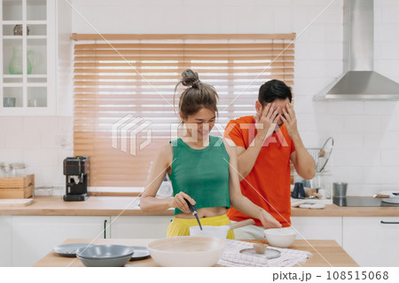 Lover couple. Funny shocked face reaction of husband looking at wife cooking. Lover couple. Funny shocked face reaction of husband looking at wife cooking. 108515068