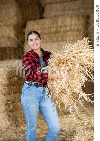 Cheerful woman farmer holding bunch of hay 108516000