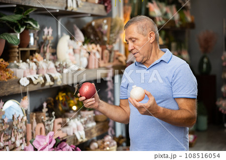 Man selecting christmas baubles in store 108516054