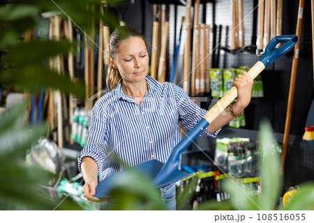 Woman choosing shovel in store 108516055