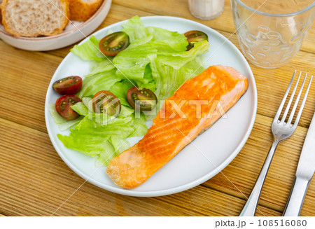 Mediterranean cuisine.slice of fried salmon with green salad and cherry tomatoes, white bread Mediterranean cuisine.slice of fried salmon with green salad and cherry tomatoes, white bread 108516080