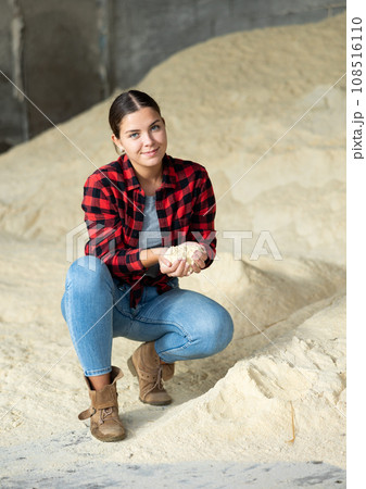 Positive woman agronomist squatting at bunch of corn flour Positive woman agronomist squatting at bunch of corn flour 108516110