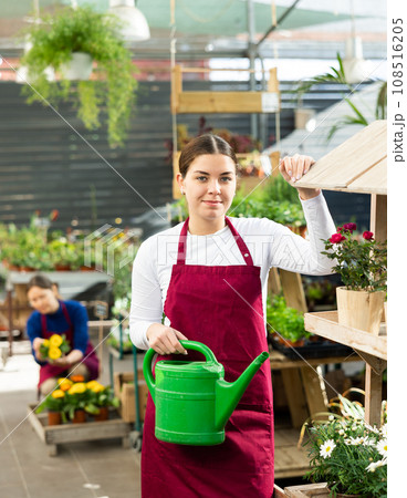 Woman seller holding watering can in flower shop Woman seller holding watering can in flower shop 108516205