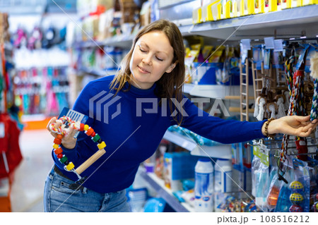 Young woman choosing toys for four-legged friend in pet shop Young woman choosing toys for four-legged friend in pet shop 108516212