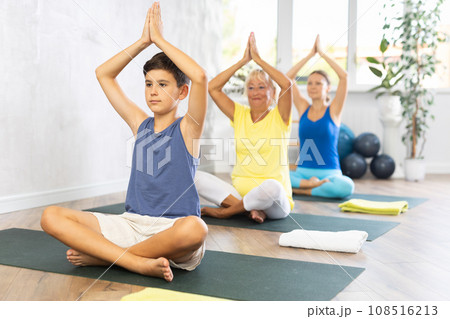 Preteen boy practicing lotus pose of yoga in light fitness room Preteen boy practicing lotus pose of yoga in light fitness room 108516213