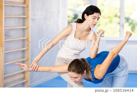 Woman is practicing self defence moves in pair with her female trainer at gym Woman is practicing self defence moves in pair with her female trainer at gym 108516414