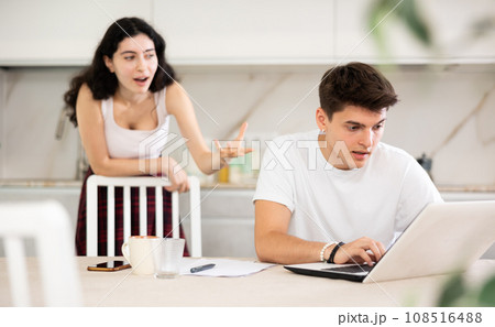 Young woman quarrels with young guy working at laptop Young woman quarrels with young guy working at laptop 108516488