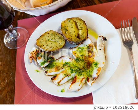 fried potato halves with fried cuttlefish topped with spicy white garlic sauce on white plate fried potato halves with fried cuttlefish topped with spicy white garlic sauce on white plate 108516626