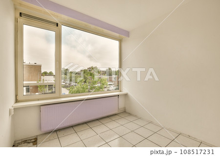 an empty room with white tile flooring and purple painted window sims on the right side of the room an empty room with white tile flooring and purple painted window sims on the right side of the room 108517231