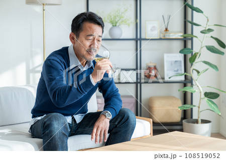 リビングで白ワインを飲むミドルの男性　 108519052