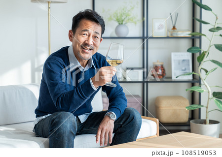 リビングで白ワインを飲むミドルの男性　 108519053