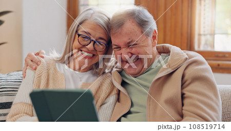 Tablet, social media and a senior couple laughing in the living room of their home together during retirement. Technology, love and relax with funny elderly people looking at a meme on the sofa 108519714
