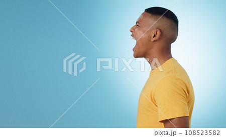 Angry, man and scream in studio at mockup space for crisis, anger or mad emoji reaction on blue background. Profile of frustrated model shouting with stress, emotional conflict or negative expression 108523582