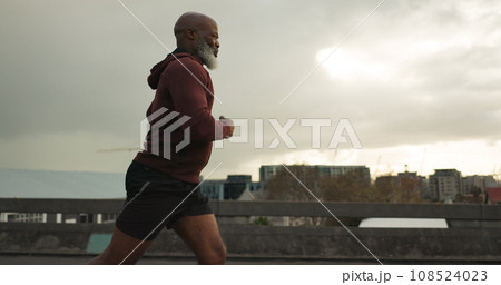 Man, city or senior runner with cardio workout in training, road fitness for health lifestyle. African athlete, retirement or wellness for strong body in leisure, cape town or exercise on urban road 108524023