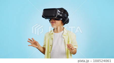 Glasses, virtual reality and child in metaverse, 3d games or futuristic technology for school or futuristic e learning in studio. Kid with high tech, VR education and watch video on a blue background Glasses, virtual reality and child in metaverse, 3d games or futuristic technology for school or futuristic e learning in studio. Kid with high tech, VR education and watch video on a blue background 108524061