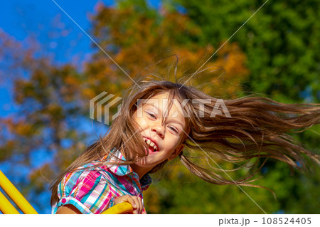Happy little girl riding on a swing outside in summertime 108524405