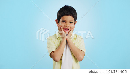 Excited, kid and hands on face for surprise in studio isolated on a blue background mockup space. Portrait, wow and happy child shocked at good news, information announcement and facial expression. 108524406