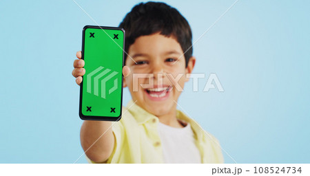Happy child, face or phone green screen in studio on social media for ecommerce, tech or download app logo. Blue background, space or kid with notification for online marketing, mockup or advertising 108524734