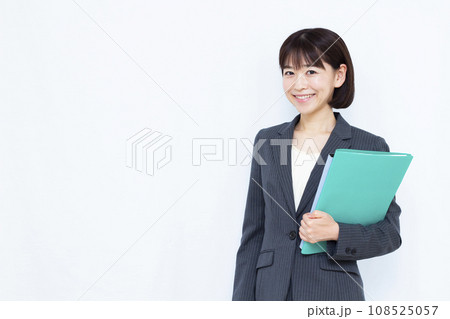 白い背景の前でファイルを持つ笑顔の30代ビジネスウーマン 白い背景の前でファイルを持つ笑顔の30代ビジネスウーマン 108525057