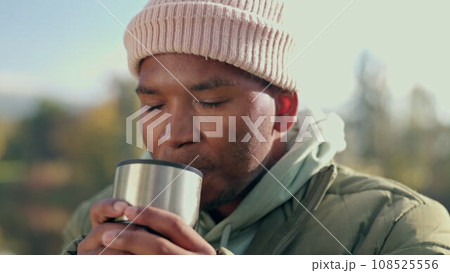 Coffee, camping and relax with black man in nature for adventure, travel and vacation. Morning, freedom and holiday with person drinking tea from mug in outdoors for peace, happy and smile Coffee, camping and relax with black man in nature for adventure, travel and vacation. Morning, freedom and holiday with person drinking tea from mug in outdoors for peace, happy and smile 108525556
