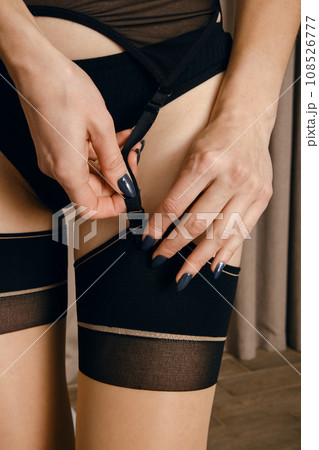 Closeup view of female hand fasten clasp of garter belt 108526777