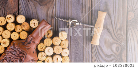 Bottle of wine with corks on wooden table background. on soft sunlight 108528003