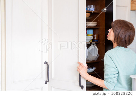 食器棚の収納に悩む女性、後ろ姿 食器棚の収納に悩む女性、後ろ姿 108528826