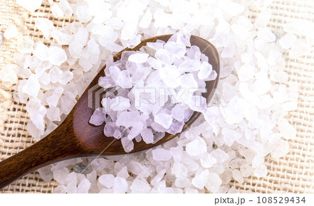 White bath salt in a wooden spoon on soft sunlight 108529434