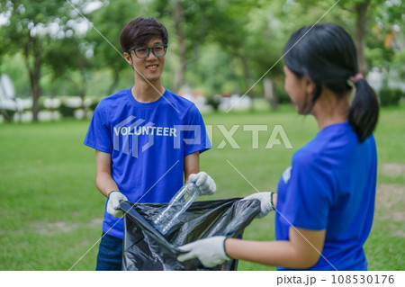 Multiethnic volunteers donate their time holding black garbage bags to collect plastic waste for recycling to reduce pollution in a public park 108530176