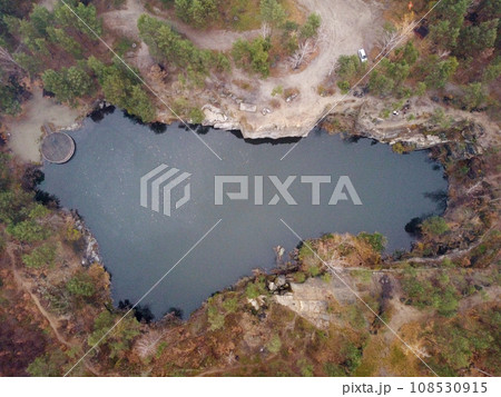 Picturesque aerial view of landscape with emerald lake and rocks in the middle of a coniferous autumn forest in Korostyshiv granite quarry, Zhytomyr district, northern Ukraine. Zhytomyr canyon 108530915