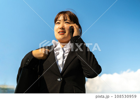 外出先で電話対応をするスーツの女性 外出先で電話対応をするスーツの女性 108530959