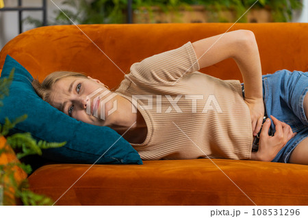 Sick ill woman suffering from period cramps, stomach ache menstrual pain lying on sofa at home room Sick ill woman suffering from period cramps, stomach ache menstrual pain lying on sofa at home room 108531296